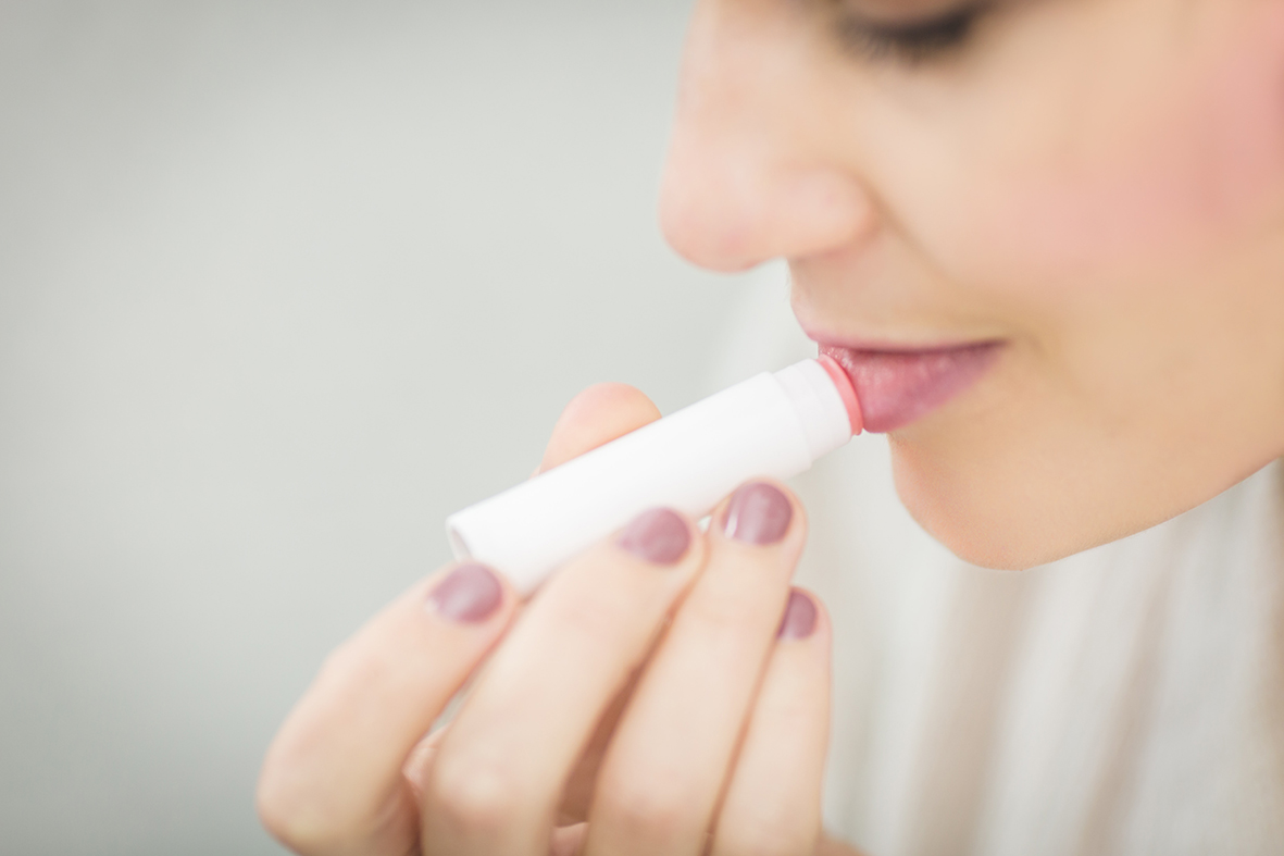 A woman applies a lip balm made from natural raw materials to her lips.